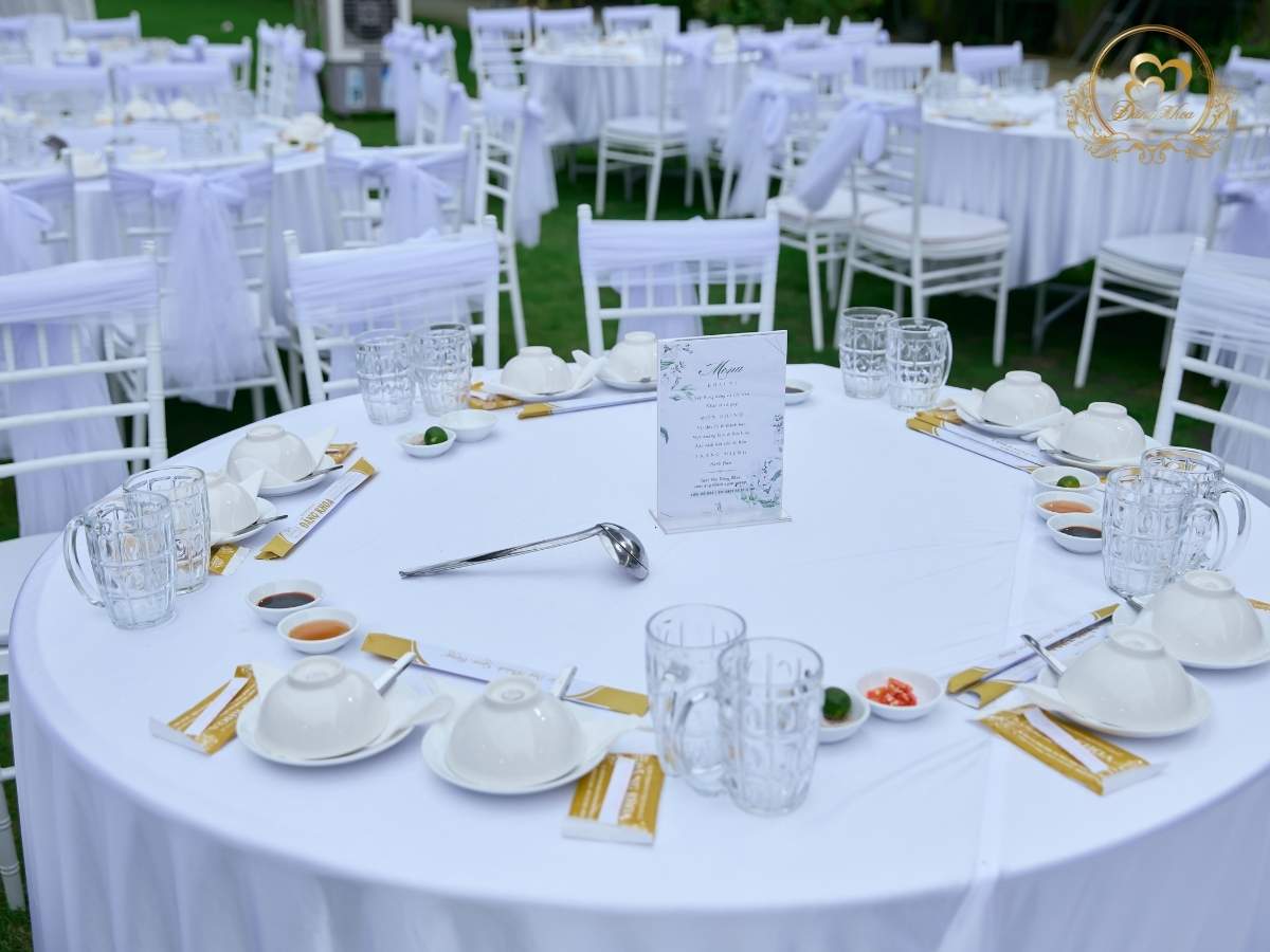 Setup bàn tiệc cưới ngoài trời: Menu thiết kế riêng ghế tiffany được thắt nơ voan trắng.