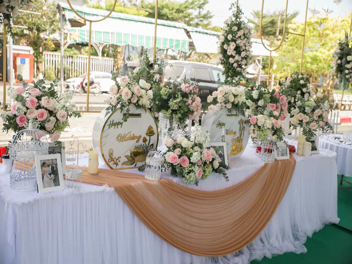 Bàn Gallery tiệc cưới Luxury: decor lồng chim, hoa bi, khung ảnh kỷ niệm.
