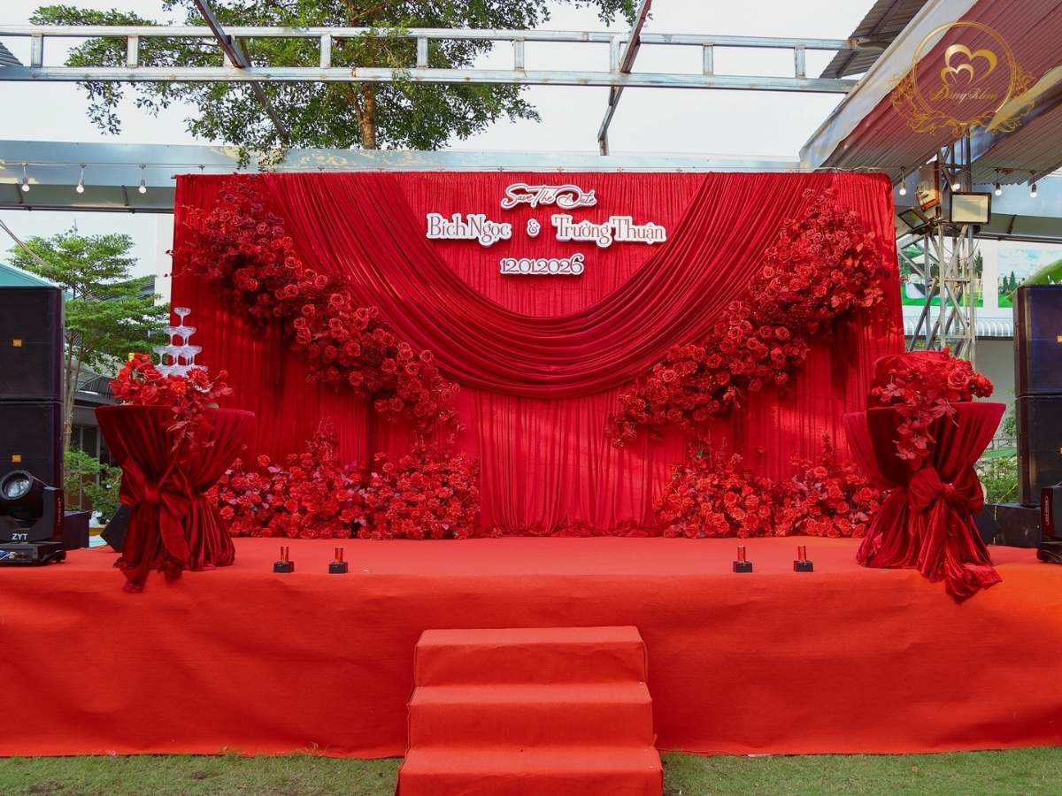 Sân khấu tiệc cưới ngoài trời tone đỏ rượu lộng lẫy.