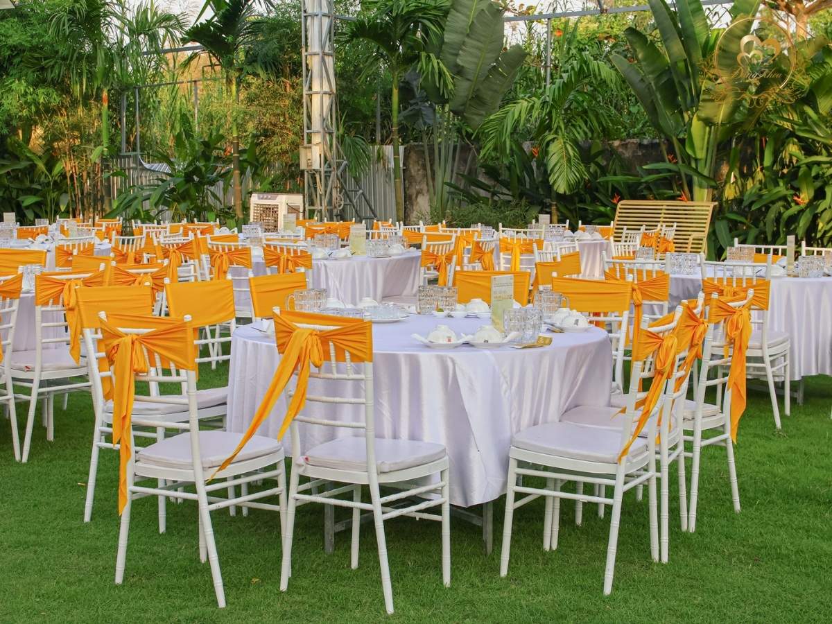 Trang trí bàn tiệc tất niên: Ghế Tiffany thắt nơ cam vàng nổi bật.